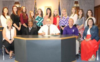 Joining Mayor Roland Boudreaux Tuesday morning at City Hall as he signed a proclamation for “Rayne High School Homecoming Week” were, seated from left, faculty sponsor Norellie Fontenot, Principal Wendall Prudhomme, Mayor Roland Boudreaux, Football Coach Curt Ware and faculty sponsor Paige Dupont; standing, court members Allison Arceneaux, Taylor Arceneaux, Tori Carriere, Haley Comeaux, Sidney Fontenot, Mia Guidry, Whitney Johnston, Katelyn LeDoux, Claire Menard, Mary Peltier and Kaitlyn Thibodeaux.